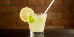 Copo de caipirinha de limão com gelo e limões frescos