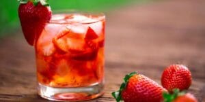 Caipirinha de morango servida em copo com gelo e morangos frescos