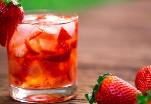 Caipirinha de morango servida em copo com gelo e morangos frescos