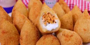 Coxinha dourada perfeita e crocante servida em um prato.