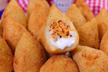 Coxinha dourada perfeita e crocante servida em um prato.