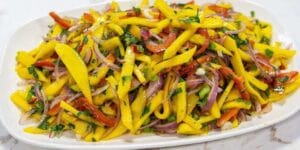 Salada com manga, pimentão e cebola roxa servida em tigela.