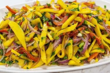 Salada com manga, pimentão e cebola roxa servida em tigela.