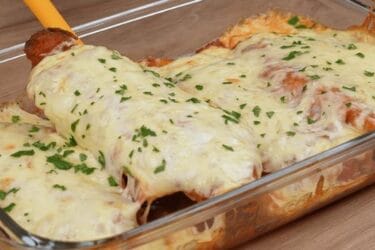 Frango à parmegiana servido com molho de tomate e queijo derretido.