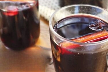 Quentão de vinho servido em copo com canela e especiarias.