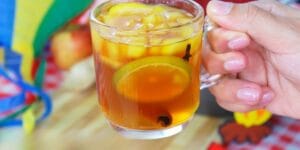 Quentão tradicional servido em copo, com frutas e especiarias.