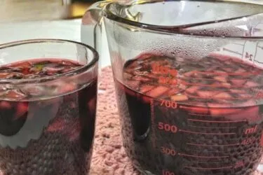 Vinho quente servido em copo, com canela e cravo.