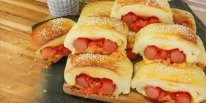 Cachorro-quente de forno cortado em pedaços, com recheio de salsicha, queijo e molho