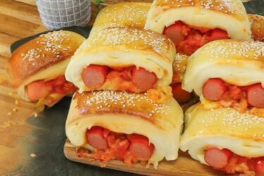 Cachorro-quente de forno cortado em pedaços, com recheio de salsicha, queijo e molho