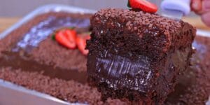 Bolo de chocolate recheado com cobertura cremosa, confeitos de chocolate e morangos frescos