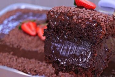 Bolo de chocolate recheado com cobertura cremosa, confeitos de chocolate e morangos frescos