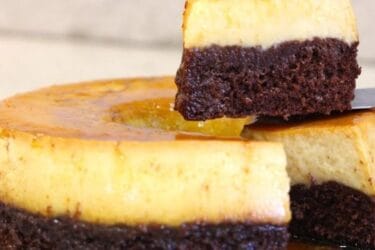 Bolo pudim com camadas de chocolate e pudim cremoso servido em fatia