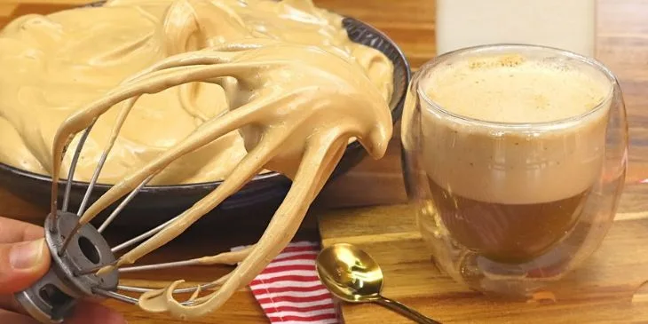 Café cremoso na batedeira servido em xícara branca com leite quente