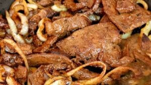 Bife de fígado acebolado com cebolas douradas em frigideira