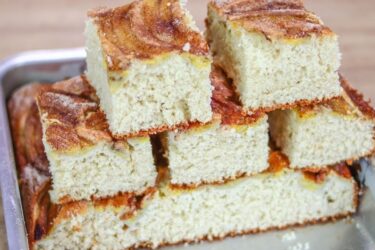 Bolo de banana de liquidificador fofinho com bananas fatiadas por cima