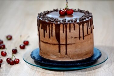 Bolo de chocolate com ganache escorrendo e cerejas