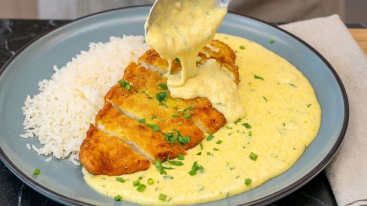 Prato de almoço com uma concha de creme de milho com frango empanado crocante e dourado.