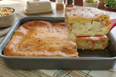 Pedaço de torta de palmito cremosa de liquidificador decorada com orégano, mostrando o recheio suculento por dentro.