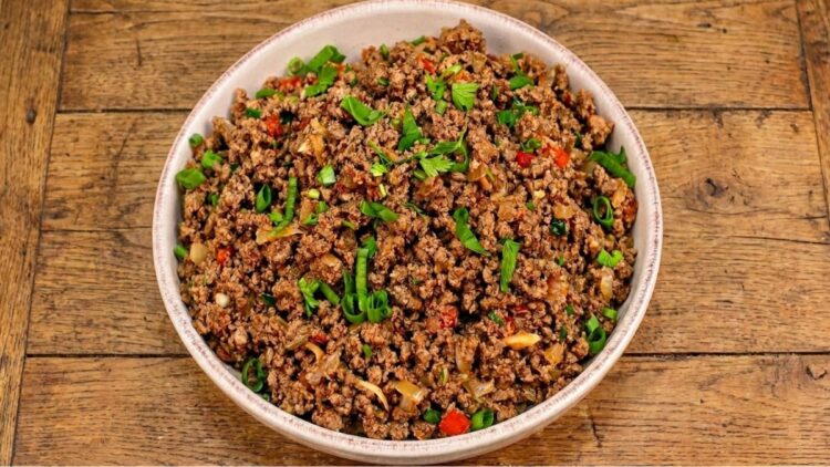 Panela com carne moída refogada bem soltinha e brilhante, salpicada com cheiro-verde fresco por cima.