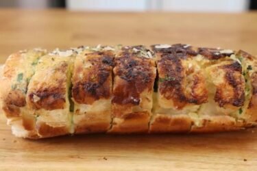 Pão de alho profissional especial para churrasco assado na grelha, douradinho, com queijo derretido e cheiro-verde por cima.