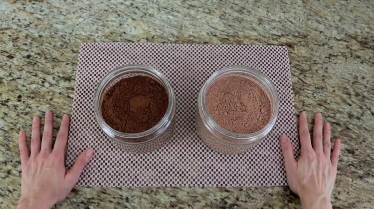 Dois potes na bancada da cozinha, um com chocolate em pó escuro e outro com achocolatado claro