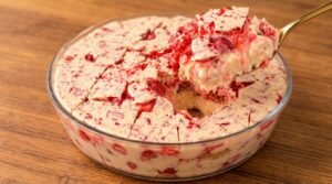 Travessa com pavê de morango cravejado, mostrando a camada de chocolate branco com pedacinhos de caramelo vermelho por cima e camadas de creme de morango.