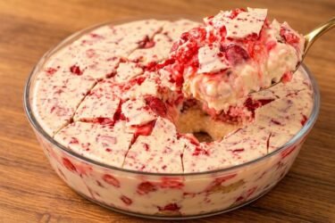 Travessa com pavê de morango cravejado, mostrando a camada de chocolate branco com pedacinhos de caramelo vermelho por cima e camadas de creme de morango.