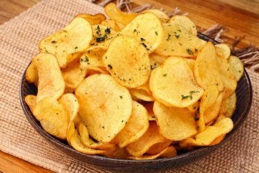 Tigela cheia de chips de batata doce frita crocante e sequinha bem douradas e temperadas.