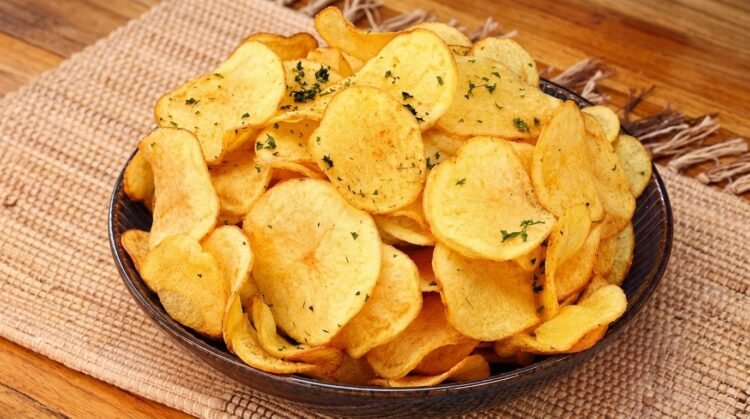 Tigela cheia de chips de batata doce frita crocante e sequinha bem douradas e temperadas.