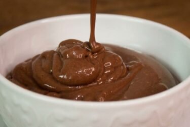 Potinhos de vidro preenchidos com Danette caseiro super cremoso de chocolate, mostrando a textura aveludada em uma colher.