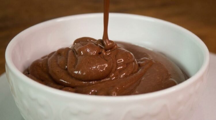Potinhos de vidro preenchidos com Danette caseiro super cremoso de chocolate, mostrando a textura aveludada em uma colher.