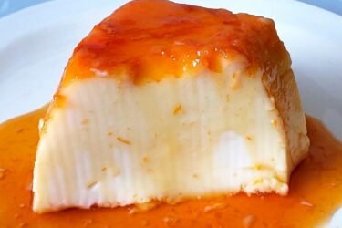 Pudim de maizena sem forno desenformado em prato raso com calda de caramelo brilhante escorrendo pelas laterais.