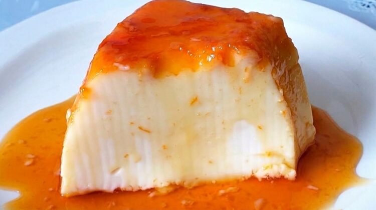 Pudim de maizena sem forno desenformado em prato raso com calda de caramelo brilhante escorrendo pelas laterais.