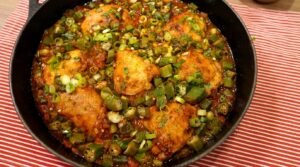 Panela com frango com quiabo ensopado e rodelas de quiabo verdinho sem baba, salpicado com cheiro-verde fresco.