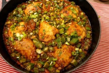 Panela com frango com quiabo ensopado e rodelas de quiabo verdinho sem baba, salpicado com cheiro-verde fresco.