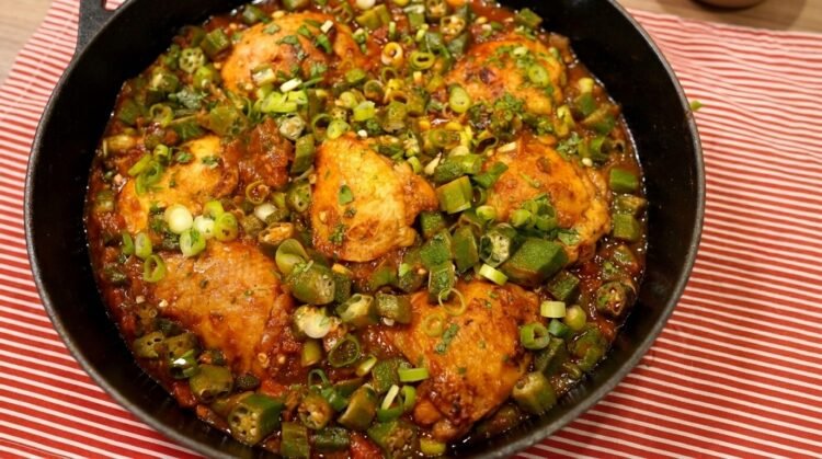 Panela com frango com quiabo ensopado e rodelas de quiabo verdinho sem baba, salpicado com cheiro-verde fresco.