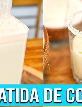 Batida de Coco cremosa em copo com gelo, coco ralado e pedaços de coco.