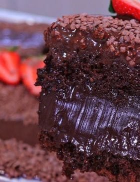 Bolo de chocolate recheado com cobertura cremosa, confeitos de chocolate e morangos frescos