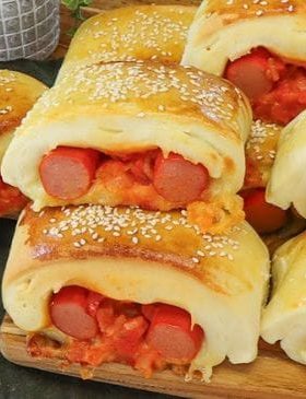 Cachorro-quente de forno cortado em pedaços, com recheio de salsicha, queijo e molho