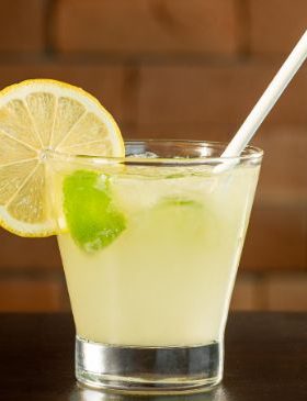 Copo de caipirinha de limão com gelo e limões frescos