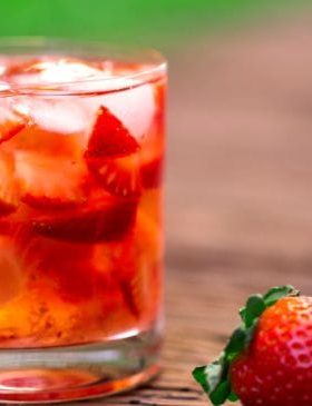 Caipirinha de morango servida em copo com gelo e morangos frescos