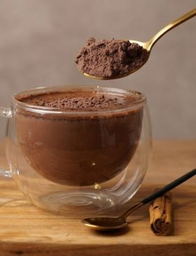 Caneca de cappuccino caseiro com muita espuma e polvilhado com canela ao lado do pote com a mistura em pó.