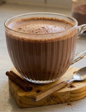 Caneca de cappuccino de chocolate caseiro com muita espuma, decorada com raspas de chocolate por cima.