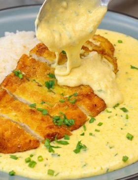 Prato de almoço com uma concha de creme de milho com frango empanado crocante e dourado.