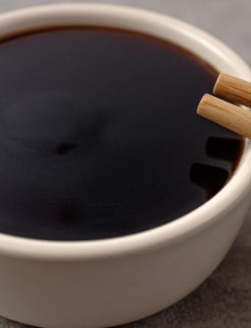 Molho teriyaki em uma tigela com gengibre ralado ao lado