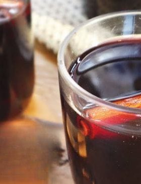 Quentão de vinho servido em copo com canela e especiarias.