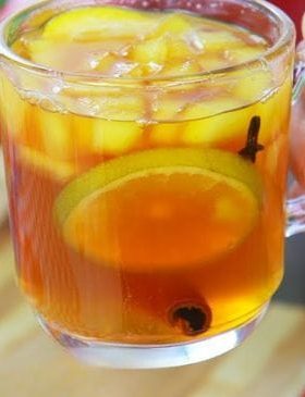 Quentão tradicional servido em copo, com frutas e especiarias.