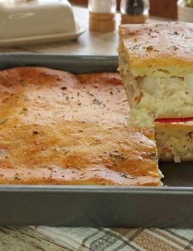 Pedaço de torta de palmito cremosa de liquidificador decorada com orégano, mostrando o recheio suculento por dentro.